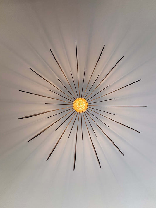 Lustre fleur design en bois projetant des ombres en forme de pétales sur le plafond, créant une ambiance chaleureuse.